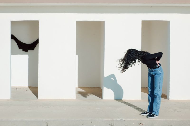 Side view full length of woman standing by wall