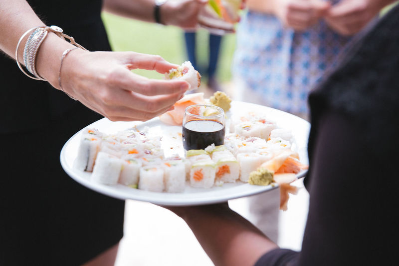 Waiter holding sushis in plate while woman eating