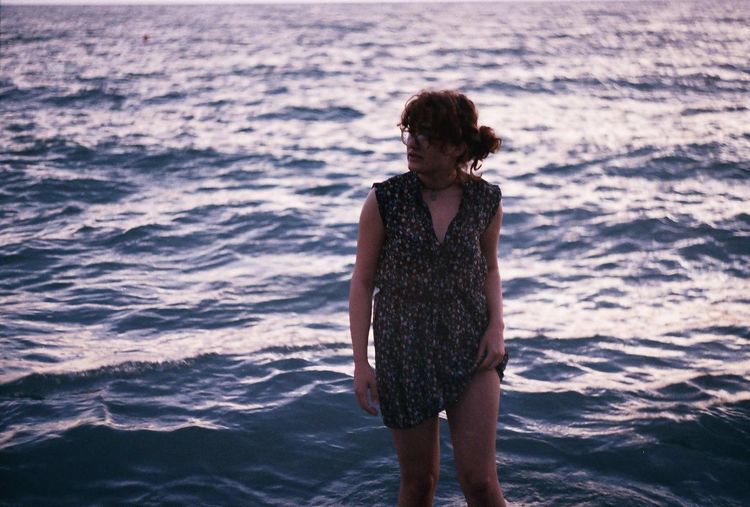 Young woman standing in sea during sunset