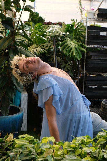 Cross dressing man dancing in greenhouse looking at flower plants