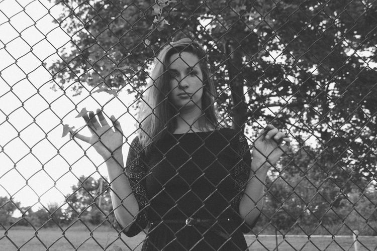 Portrait of woman behind chainlink fence