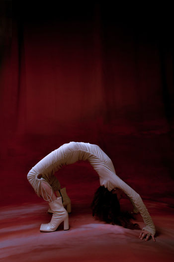 Midsection of man dancing against red wall