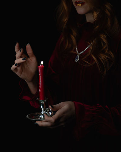 Woman holding a red candle in the dark