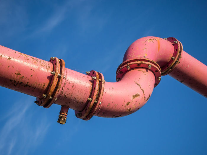Low angle view of pink pipe against blue sky