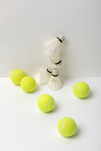 High angle view of tennis ball with shuttle cock against white background
