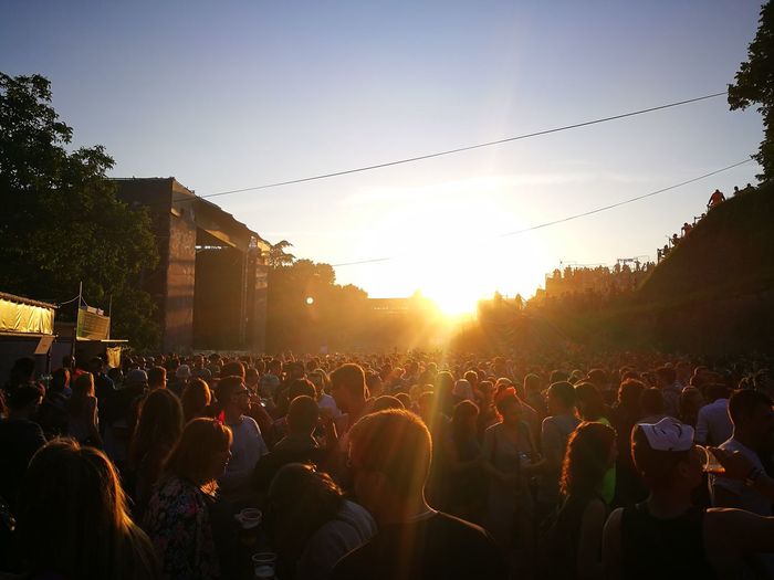 Crowd at concert against sky during sunset