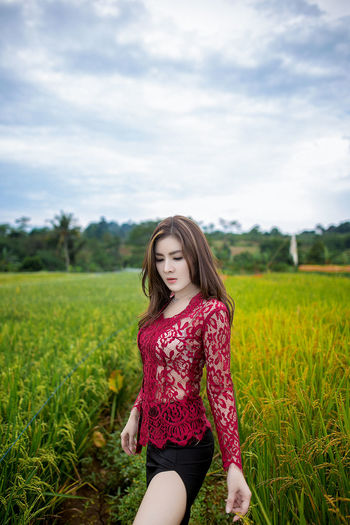 Beautiful young woman on field against sky