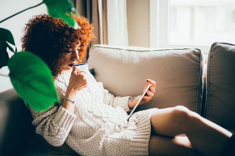 Midsection of woman using mobile phone while sitting on sofa at home