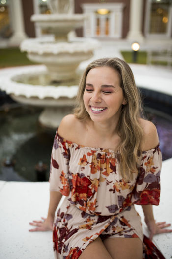 College student laughing by a fountain in a courtyard