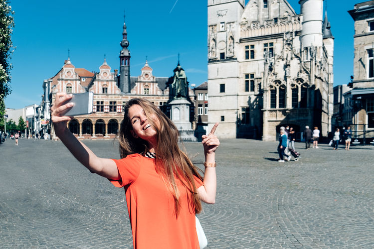 Pretty young woman taking a selfie in historic center of a belgian, european town