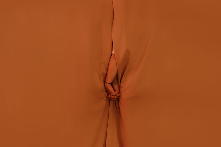 WOMAN STANDING AGAINST ORANGE WALL