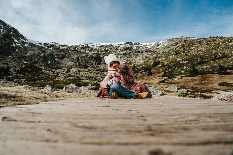 Couple sitting on mountain against sky