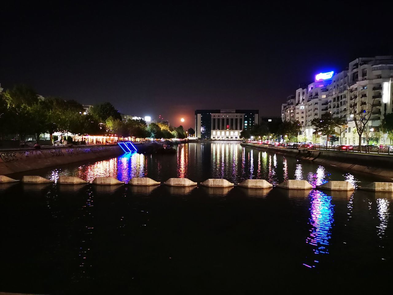 ILLUMINATED BUILDINGS BY RIVER AT NIGHT
