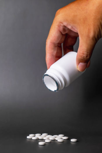 Cropped hand holding bottle against black background