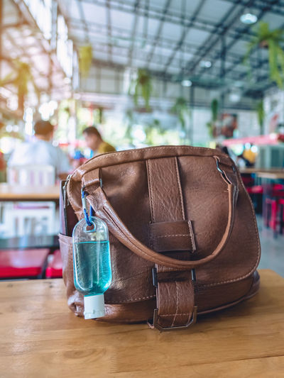 Mini portable alcohol gel bottle to kill corona virus covid-19 hang on brown leather shoulder bag 