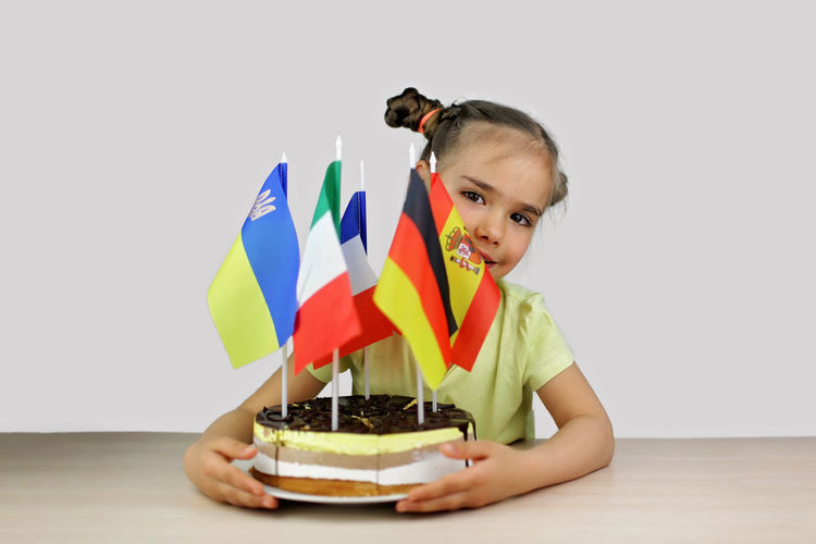 Girl holds baked cake with several european flag and ukrainian one also. europe and euro integration