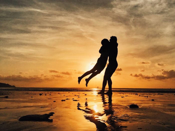Silhouette couple enjoying at beach during sunset