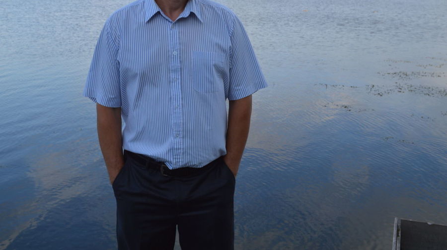 Midsection of man standing against lake