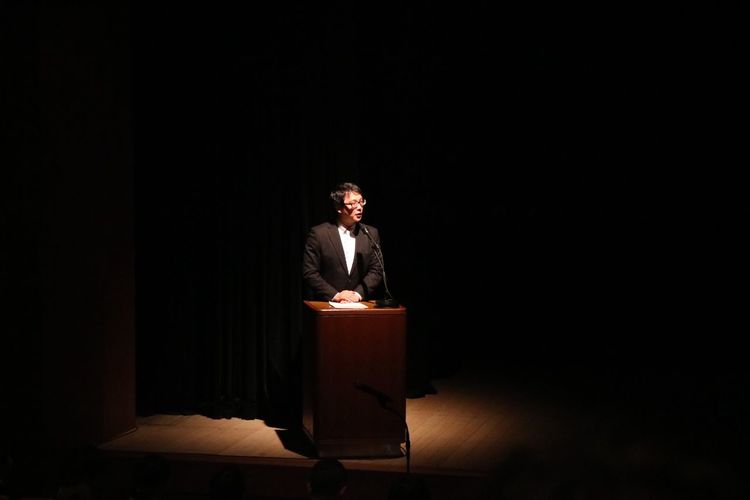 Mid adult man looking away while giving speech on stage