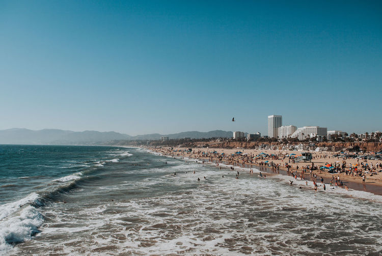 Santa monica beach view with waves crashing and mountains in the background on a clear sunny day