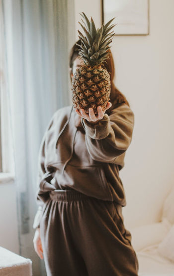 Midsection of person holding a pineapple at home