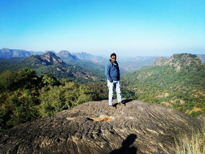 Full length of man standing on mountain against clear blue sky