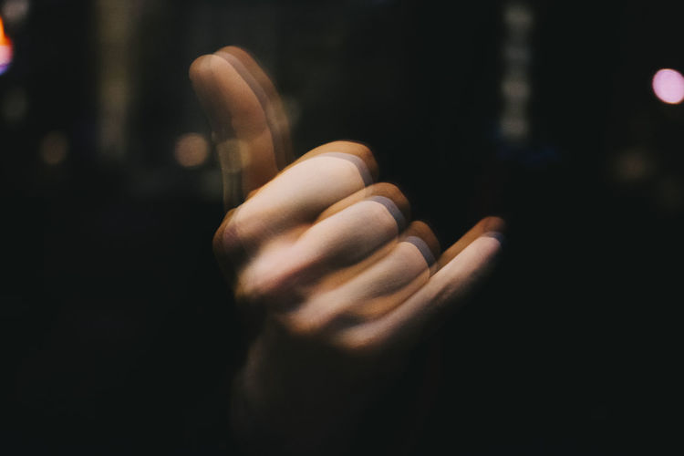 Blurred motion of hand gesturing shaka sign in darkroom