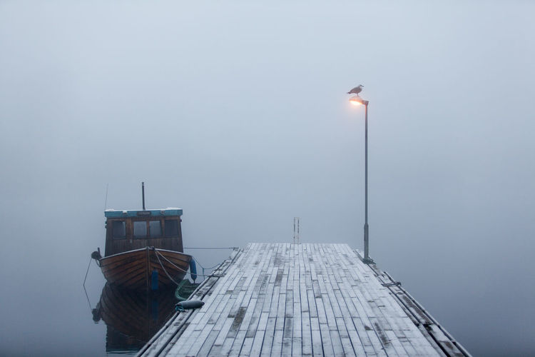 Lone boat moored at jetty in calm lake