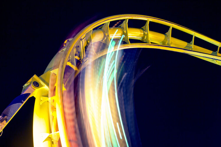 Low angle view of illuminated rollercoaster at night