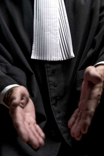 Midsection of lawyer gesturing against black background