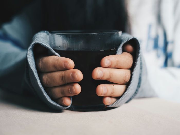 Cropped image of person holding hot drink at home