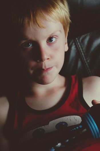 Close-up portrait of boy playing video game while sitting on sofa