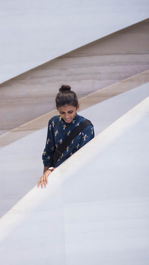 Young woman looking down while standing by retaining wall