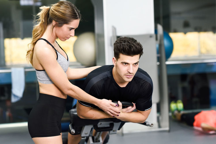 Trainer assisting man at gym