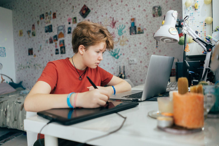 Side view of boy using laptop at home