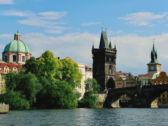 Bridge over river by buildings against sky