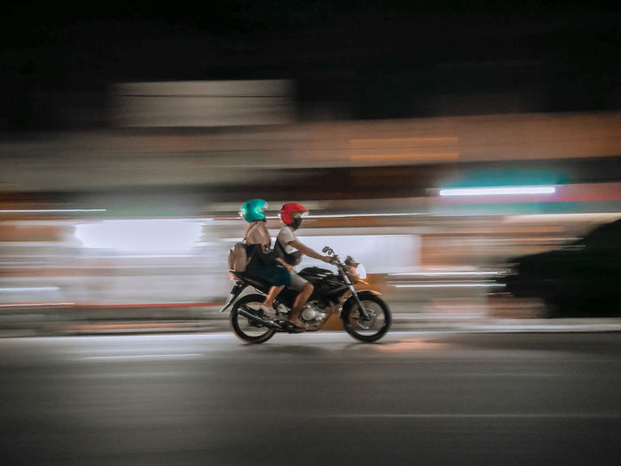 Man riding motor scooter on street at night