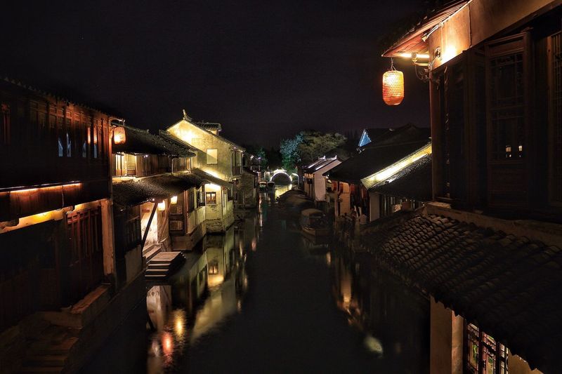Canal amidst houses at night