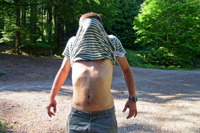 Man covered face with t-shirt while standing on footpath