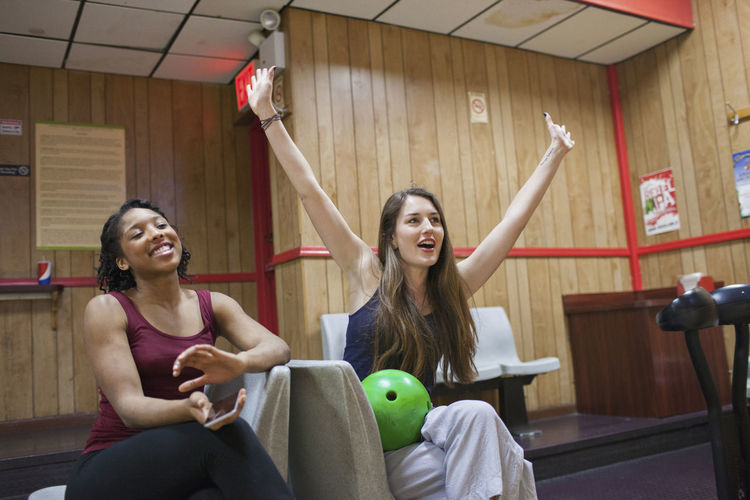 Two young women chereing at a bowling alley.