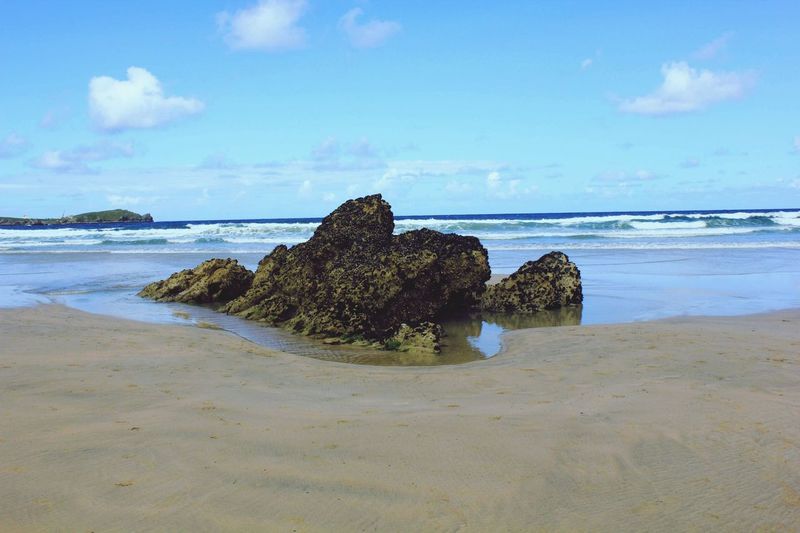 Rocks at beach against blue sky
