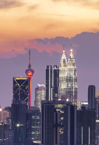 Modern buildings in city against sky during sunset