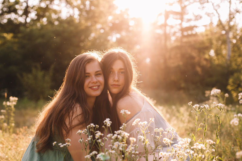 Portrait of happy lesbian couple sitting amidst flowers in summer