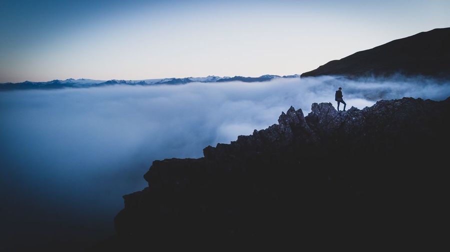 Silhouette man standing on mountain against cloudscape