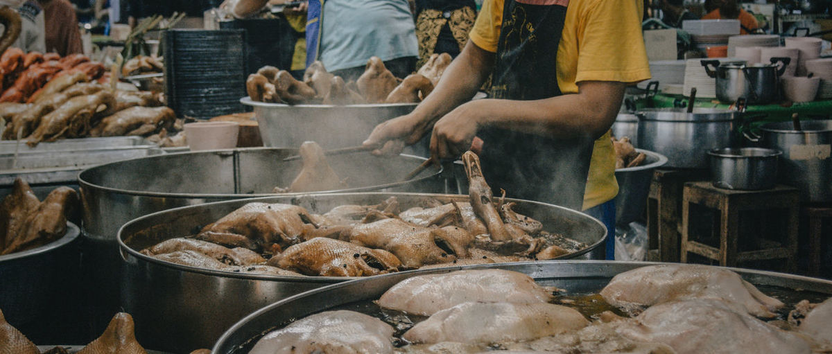 Side view of man cooking meat in don wai market