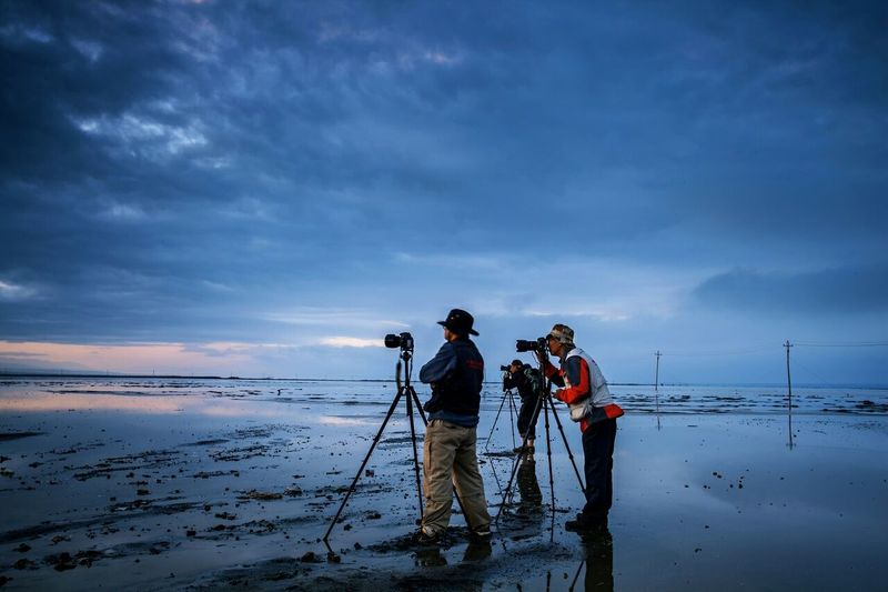 Men photographing at beach during sunset