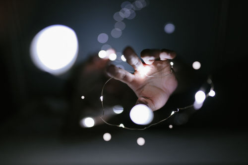 Cropped hands with illuminated string lights in darkroom