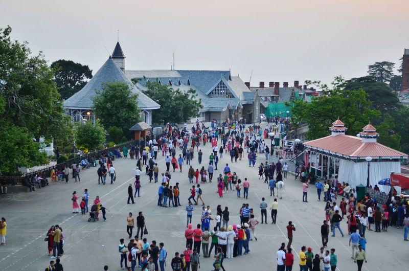 Crowd in town square against clear sky during sunset