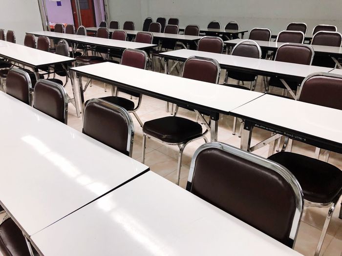 Empty chairs arranged at tables in lecture hall