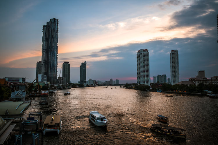 Panoramic view of chao phraya river and buildings against sky during sunset